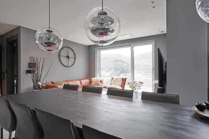 グレーのトーンのリビングとダイニング、ブラウンレザーソファと長いダイニングテーブルが配置されたモダンなインテリア