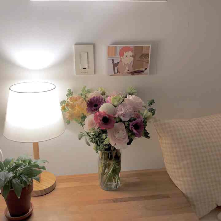 Natural color bedroom desk featuring a vase of flowers and table lamp in a cozy setting