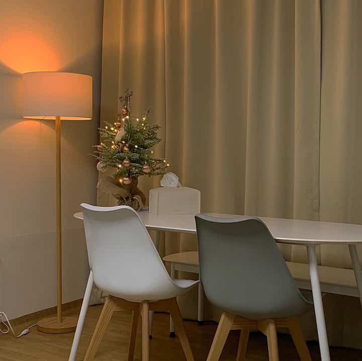 Natural-tone brown wood floor and beige blackout curtains in a dining room, with a white dining table and two-tone chairs creating a modern atmosphere