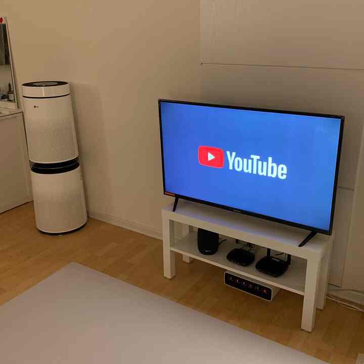 Simple white-toned living room featuring an IKEA Lack bench holding a 45-inch TV and a neatly organized multi-tap box beneath