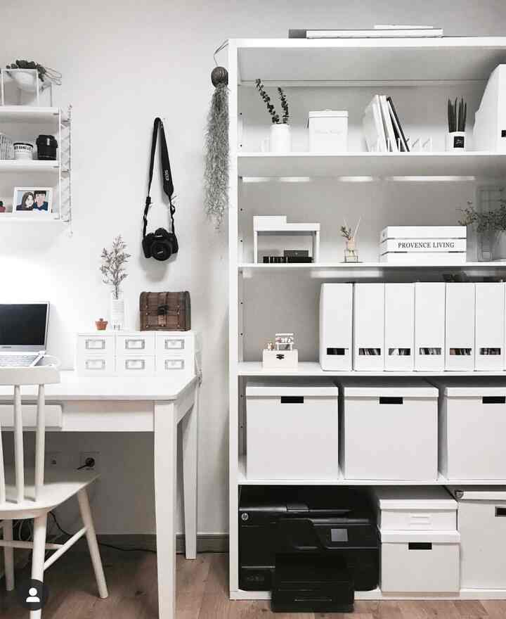 White-toned study space featuring a laptop desk, drawers, and storage units arranged in a modern interior