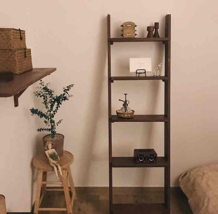 Warm natural wood-tone corner of a room featuring wooden shelves, stool, rattan accessories, and plants creating a cozy home cafe space