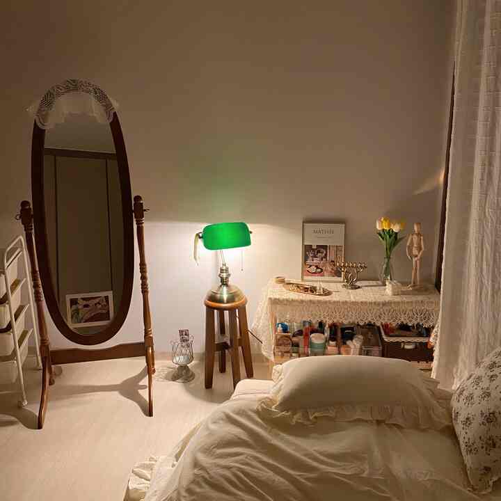 Cozy white-tone bedroom with warm lighting and natural wood accents, featuring a full-length mirror and floor lamp