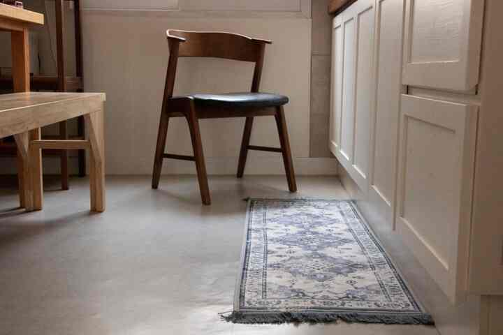 Kitchen space blending dark wood furniture and white cabinets, featuring a vintage Persian rug and mahogany dining chair in a stylish atmosphere