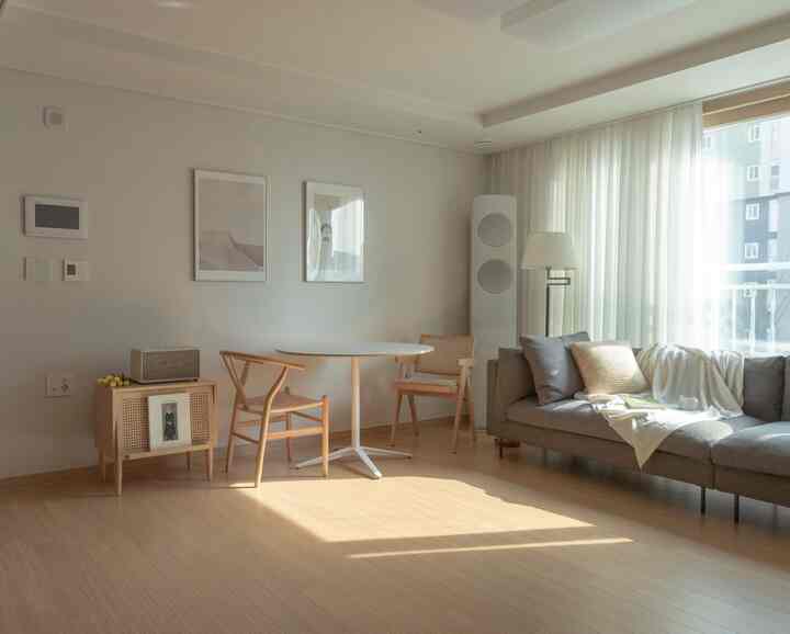 A soft white and natural wood tone living room with modern dining table and sofa creating a cozy atmosphere