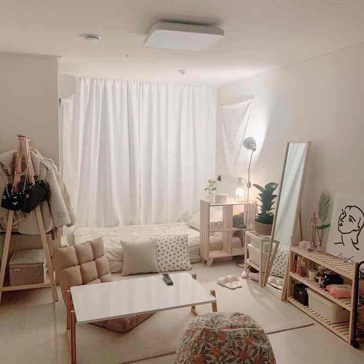 Bright beige and white toned 7.8-pyeong studio apartment with natural wooden furniture, floor sofa, and curtains creating a cozy atmosphere