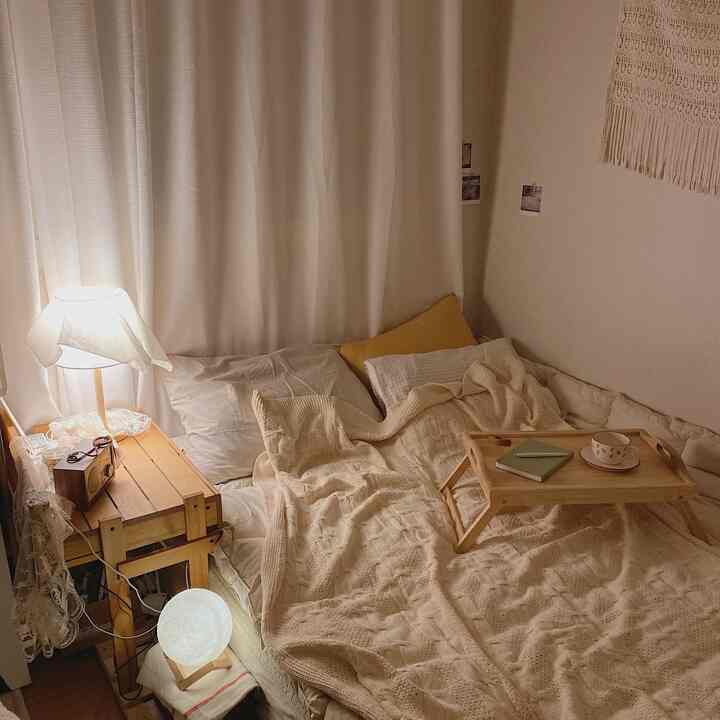 Warm beige-toned bedroom featuring wooden side table and thick knit blanket creating a cozy atmosphere