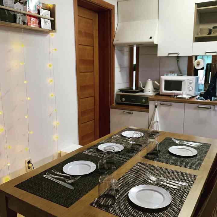 白と木目調の調和が取れたキッチン・ダイニング空間、テーブル上に並べられた皿とランチョンマットが配置された雰囲気のあるインテリア