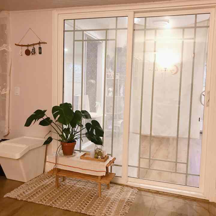 Warm beige natural-toned entrance featuring a wooden multipurpose shelf and a Monstera plant creating a cozy atmosphere