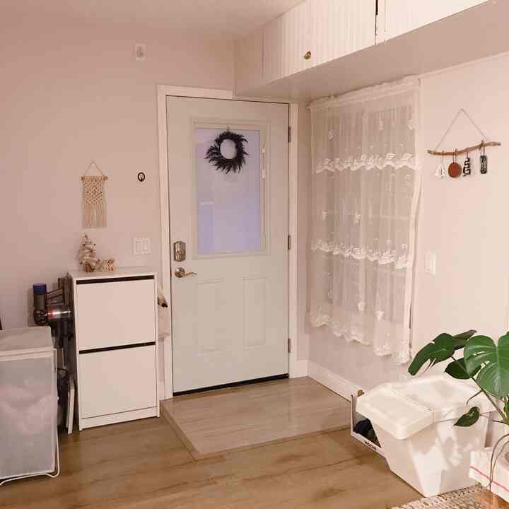 白とベージュのトーンの玄関、シューズラックと収納ボックスが配置された落ち着いた印象の空間