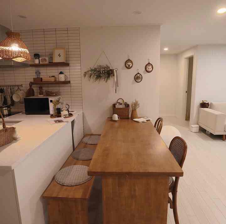 ナチュラルな木目調とラタン照明のあるキッチンと4人用の木製ダイニングテーブルが配置された、温かみのあるインテリア