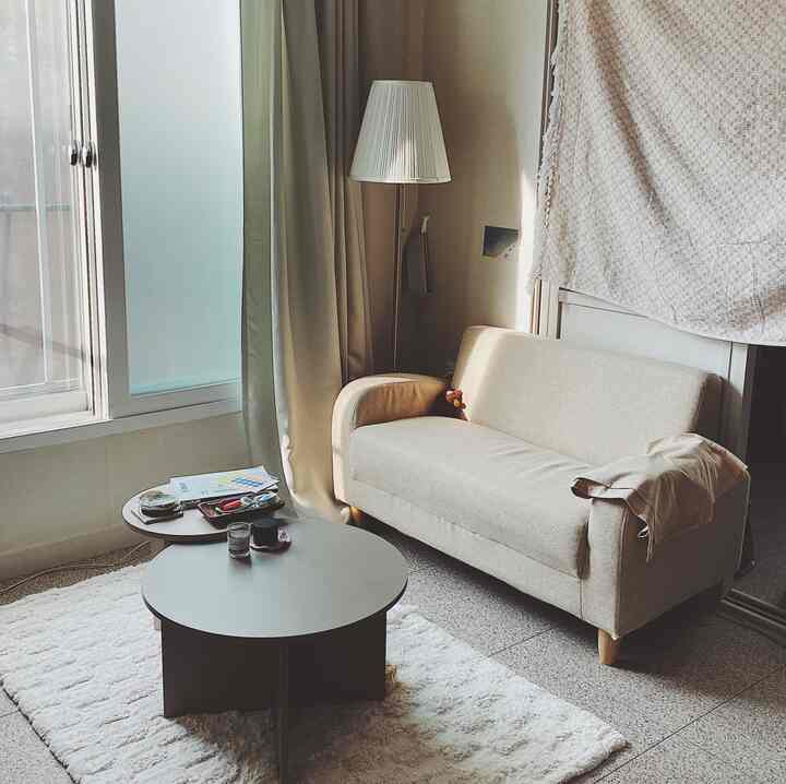 Natural beige toned living room featuring a beige sofa, round coffee tables, and a floor lamp in a cozy interior