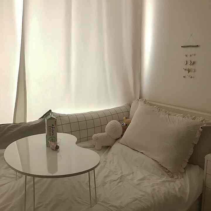 White-toned bedroom featuring a white bed and checkered sofa with a simple and cozy atmosphere