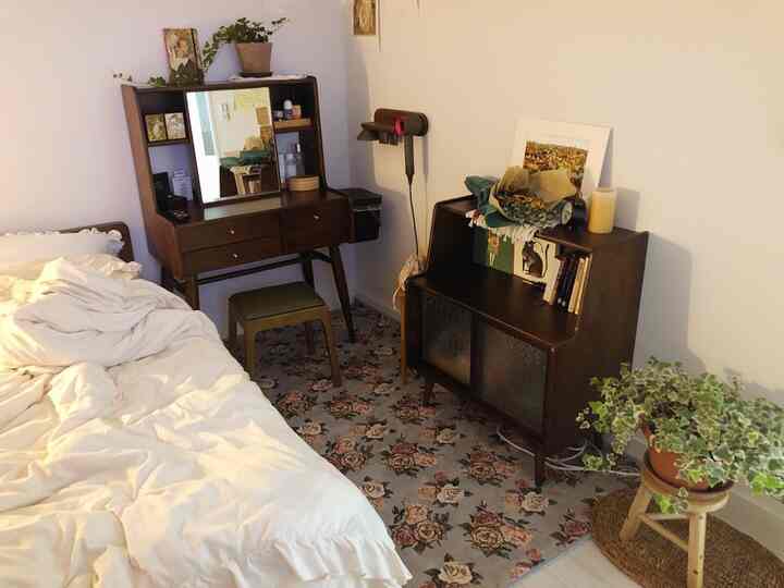 ナチュラルカラーと木目調の寝室、花柄のラグと木製家具が配置された雰囲気のある空間