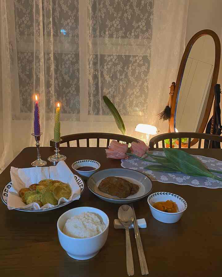 Cozy brown wooden dining table set for a single meal with lace curtains in the background