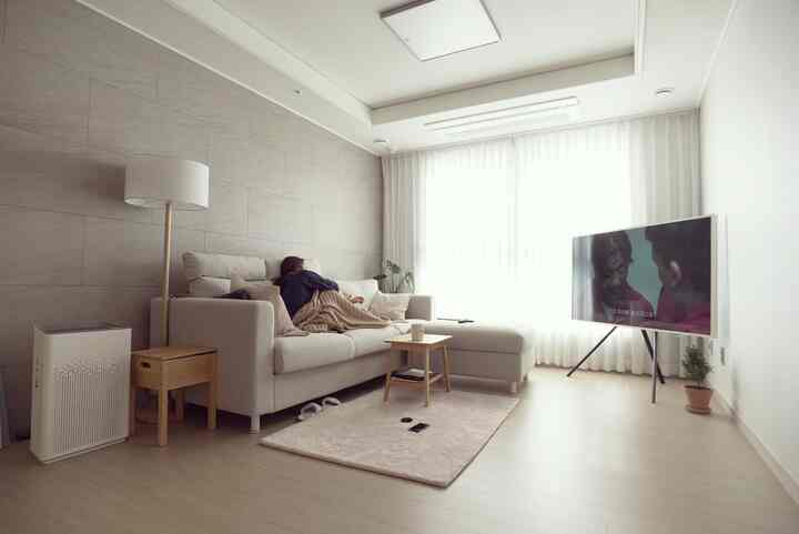Bright living room with white and beige tones featuring a beige sofa and wooden side table creating a cozy atmosphere