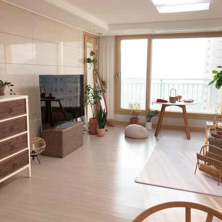 Bright white and wood-toned natural living room featuring rattan accessories and plants, creating a cozy home cafe vibe