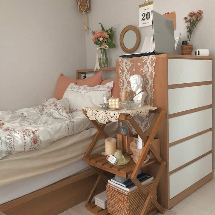 Cozy bedroom with warm wood tones and white walls, featuring vases and lace decor creating a natural ambiance