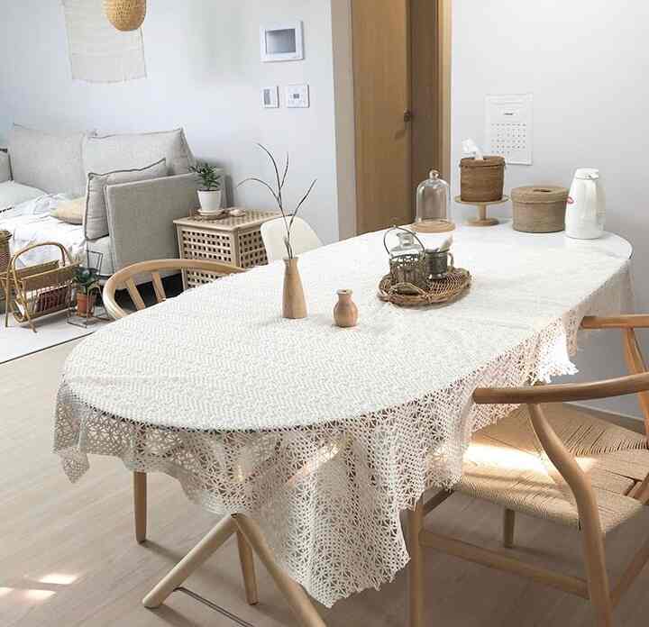 A white and brown toned kitchen featuring a wooden dining table and chairs with natural rattan accessories