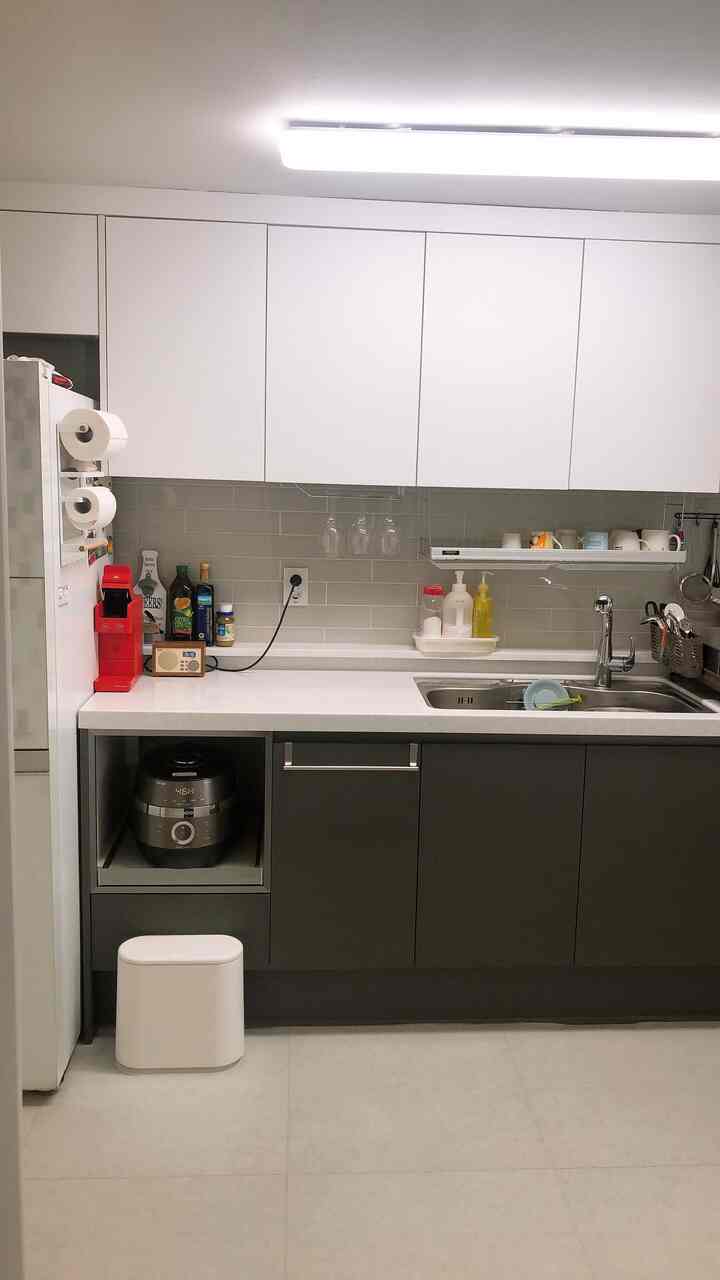 White and gray toned kitchen featuring bright, clean storage and a red coffee machine as a focal point, practical and neat space