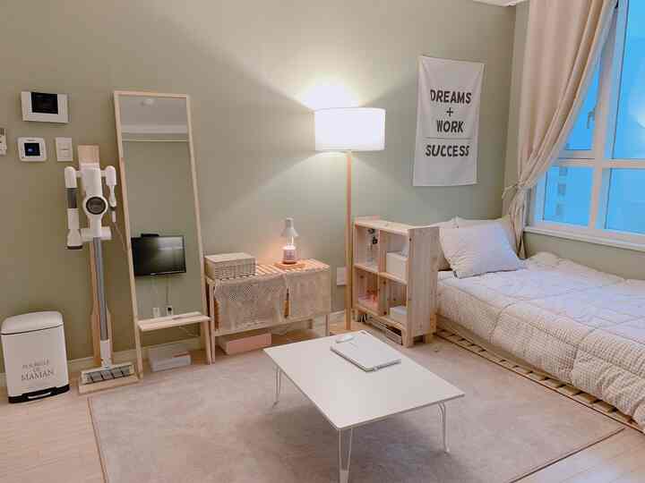 柔らかいグリーンの壁と木製家具が配置された、シンプルでナチュラルな雰囲気の寝室