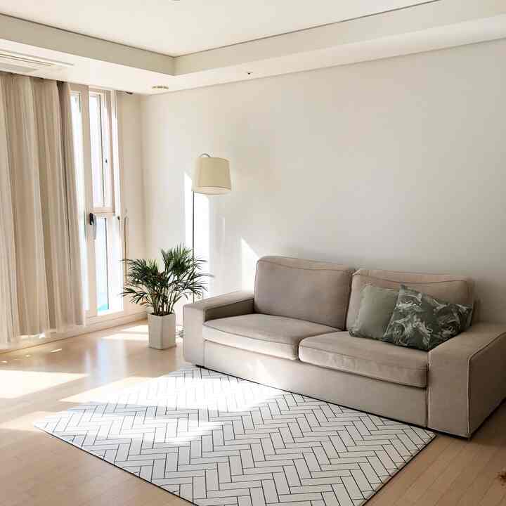 White and wood tone living room featuring beige sofa, floor lamp, and a green plant with a calm and cozy atmosphere