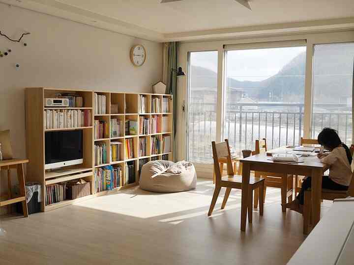 Beige and wood-tone living and study area featuring a bookshelf and dining table creating a cozy reading atmosphere