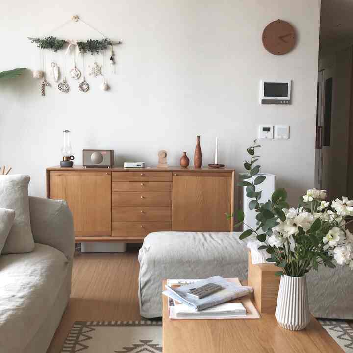 白い壁とナチュラルな木目調家具が調和するリビング、ファブリックソファと木製コーヒーテーブルが配置された雰囲気のある空間