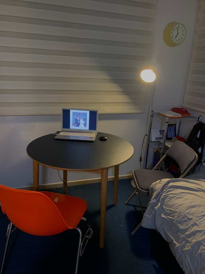 ネイビーカーペットとブラックの丸テーブルがあるワンルーム寝室、フロアランプとコンパクトな家具配置で落ち着いた雰囲気のインテリア