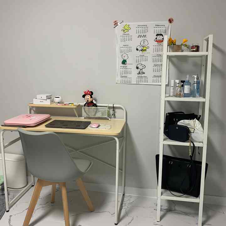 A simple and clean home office space for a single household featuring white and wood tone elements with desk and shelving in a small room