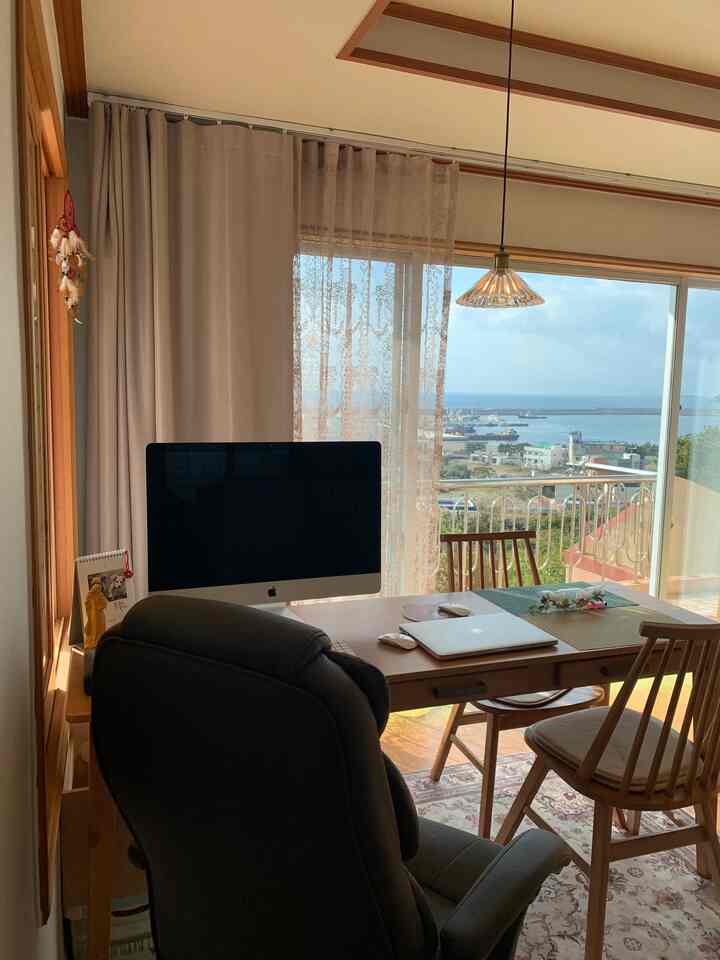 Wood tone and white home office space featuring large windows and veranda, warm atmosphere in a dining and work area