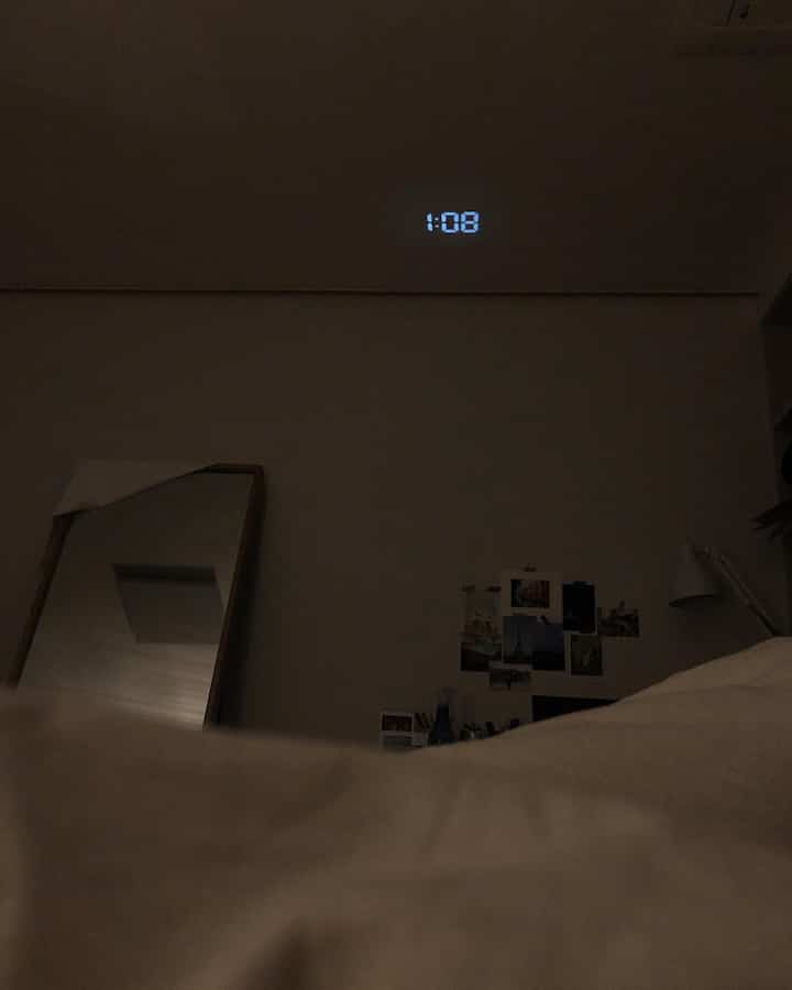 White and gray toned bedroom featuring bed and a projected clock on the wall, creating a cozy atmosphere