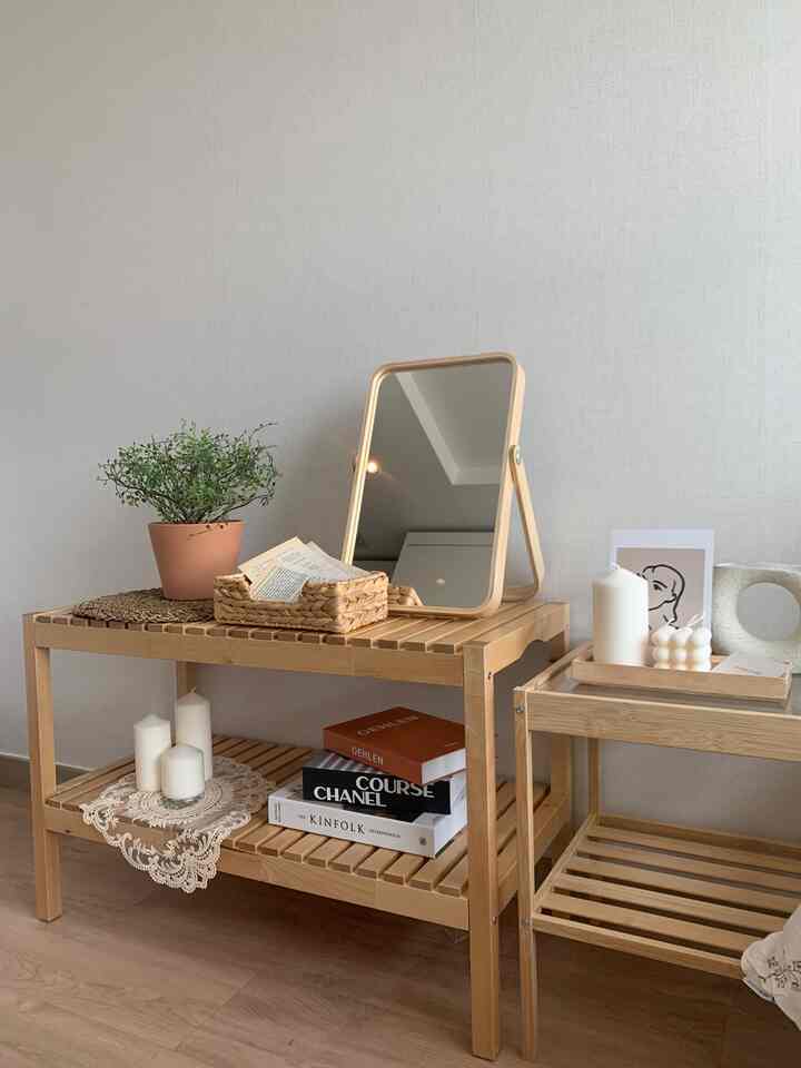 Natural color and beige toned space featuring wooden tables, a wooden mirror, candles, and a poster creating a cozy interior