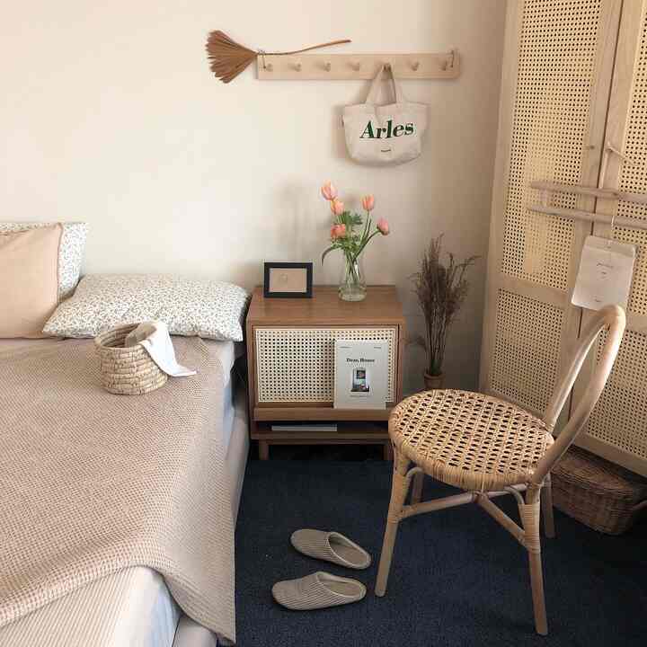 Beige and natural tone bedroom featuring rattan chair, side table with vase, and soft bedding creating a warm atmosphere