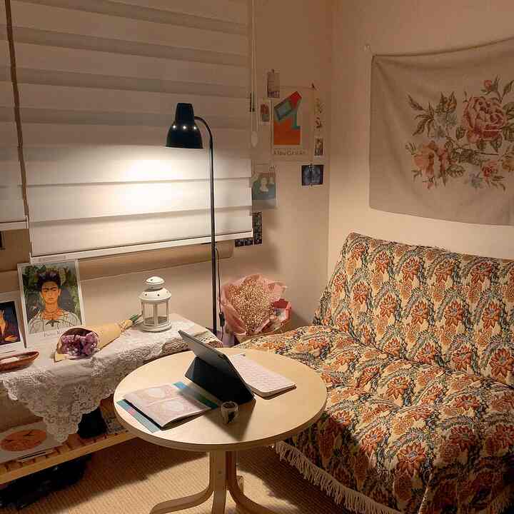 A cozy natural-toned single-person home office featuring a vintage floral sofa and floor lamp with warm atmosphere