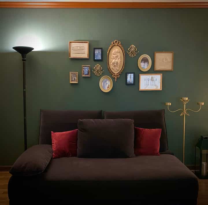深い茶色のソファと金色の額縁が配置された緑色の壁のある居心地の良いリビングルーム