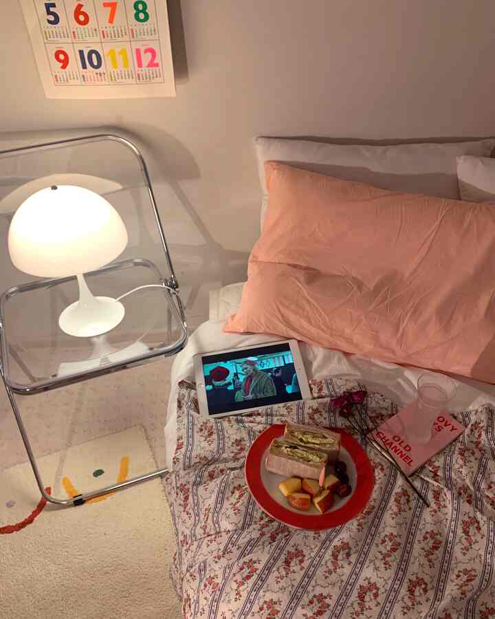 柔らかいベージュトーンの寝室、花柄のベッドカバーとオレンジ色の枕が配された温かみのあるインテリア