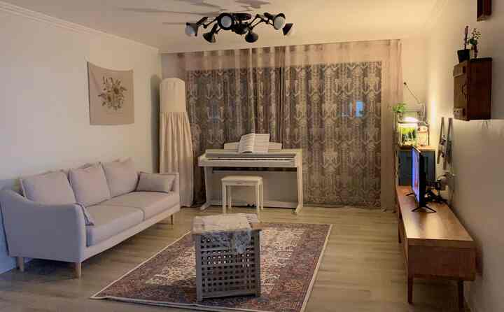 Natural color and beige toned living room featuring light gray sofa, Persian carpet, and a white piano creating a cozy ambiance