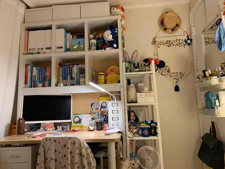 White and wood tone home office space featuring a desk and bookshelves with an organized cozy hobby room atmosphere
