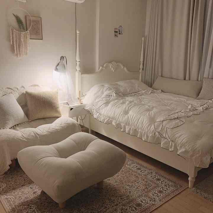 Beige and white toned bedroom featuring sofa, ottoman, and rug with cozy modern atmosphere