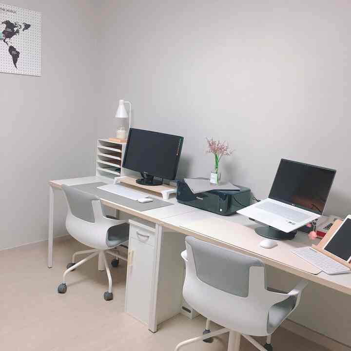 White and gray toned home office featuring dual desks and office chairs in a clean, organized workspace