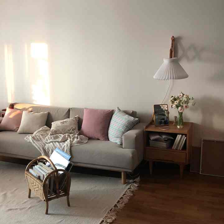 Beige and natural-toned living room featuring a gray sofa and wooden nightstand in a simple, neat space