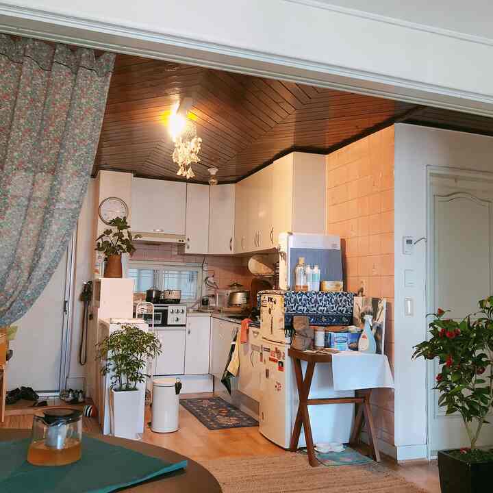 Warm wood-tone vintage kitchen featuring floral curtains and a practical compact dining table in a cozy space