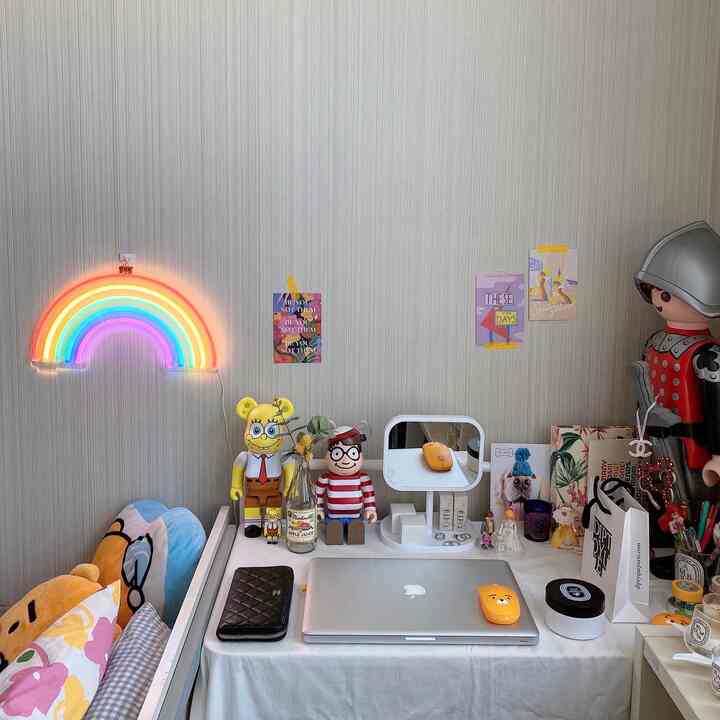 A cozy pastel-toned wall home office desk for a single household featuring a rainbow neon light and various interior accessories