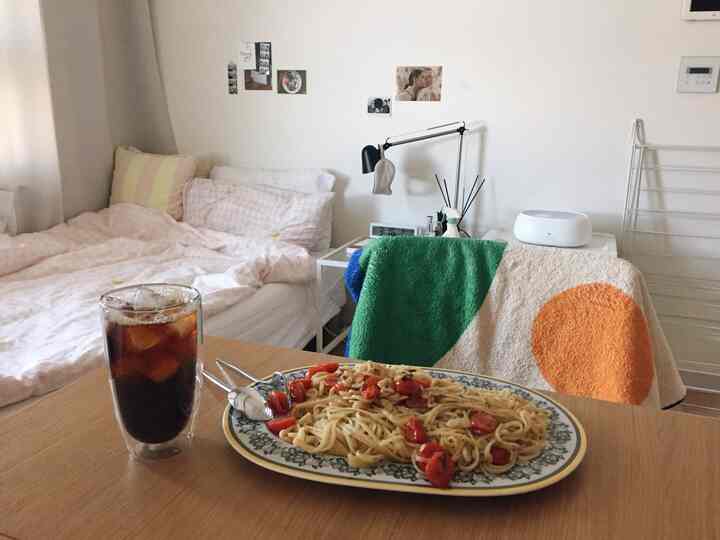 White-toned bedroom space featuring pink bedding and colorful blanket as accents in cozy studio apartment