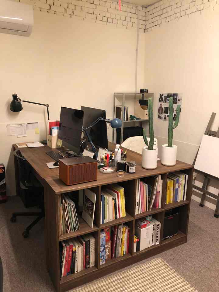 Natural-toned home office space featuring a brown desk and shelves with two computer monitors arranged in a neat workspace