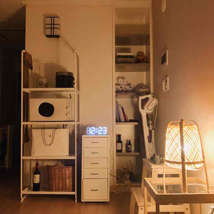 ホワイトとウッドトーンが調和した6坪のワンルーム、収納家具と棚、デジタル時計、暖かい照明が落ち着いた空間を演出
