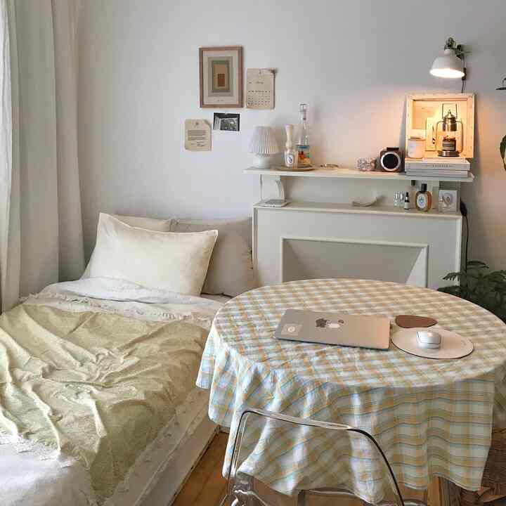 Small studio living room in white and yellow tones featuring a bed-sofa and a checkered dining table with cozy atmosphere