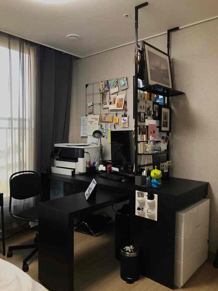 Black-toned home office space featuring an L-shaped desk and metal partition, presenting a practical and compact workspace