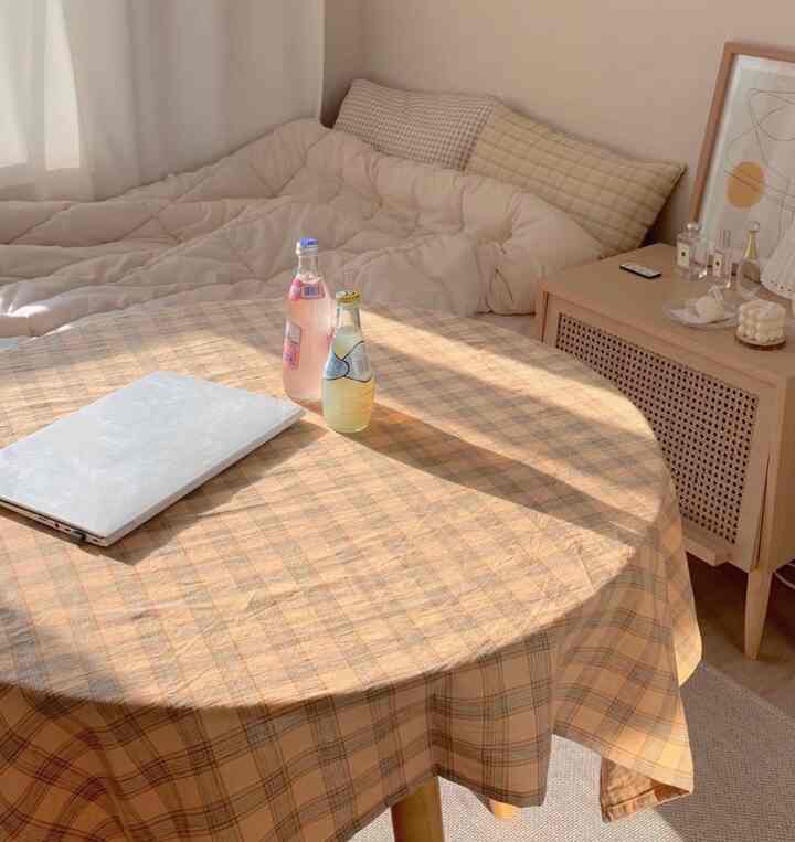 Cozy bedroom in soft beige tones featuring a table with a checkered runner and a nightstand, exuding warmth